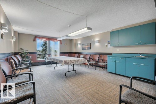 Open-concept room featuring light-colored wall paint, textured carpet tile flooring, and a window with vertical blinds - 316 2011 137 Avenue, Edmonton, AB - Indoor