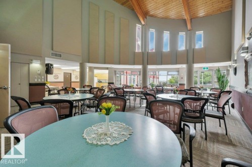Spacious communal area featuring a high vaulted wood-beam ceiling and multiple round tables - 316 2011 137 Avenue, Edmonton, AB - Indoor Photo Showing Dining Room