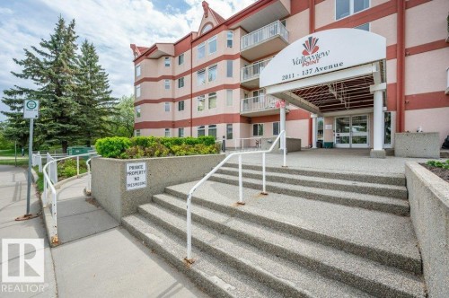 Multi-story building exterior with a covered entrance, prominent signage, and multiple balconies - 316 2011 137 Avenue, Edmonton, AB - Outdoor