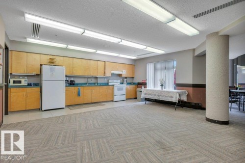 Spacious kitchen in the social room with wood-finish cabinetry and light blue countertops - 316 2011 137 Avenue, Edmonton, AB - Indoor Photo Showing Kitchen