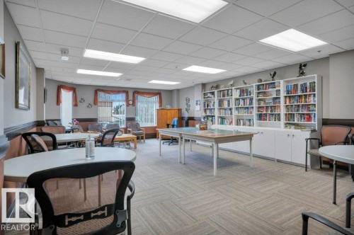 Spacious common area featuring extensive built-in shelving, recessed lighting, carpet flooring, and a series of windows with vertical blinds - 316 2011 137 Avenue, Edmonton, AB - Indoor