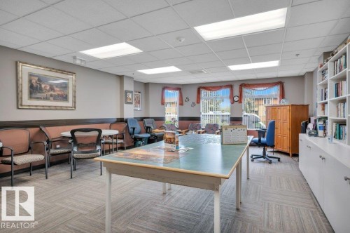 Spacious common room featuring carpet tile flooring, extensive built-in shelving, large window fixtures, and ample natural light - 316 2011 137 Avenue, Edmonton, AB - Indoor
