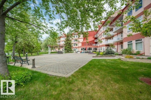 Expansive paver patio with a pergola, bordered by green lawn and mature trees - 316 2011 137 Avenue, Edmonton, AB - Outdoor