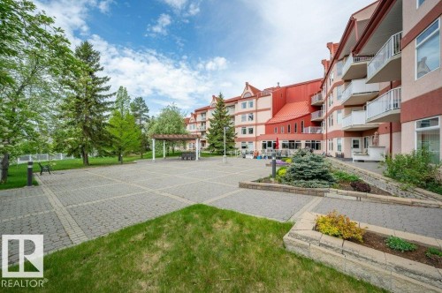Expansive paved courtyard featuring a pergola, mature trees, and landscaping - 316 2011 137 Avenue, Edmonton, AB - Outdoor With Balcony