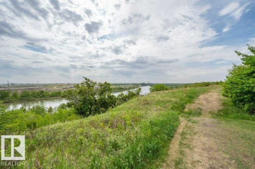Expansive natural landscape featuring a winding dirt path, lush green foliage, and distant water - 316 2011 137 Avenue, Edmonton, AB - Outdoor With View