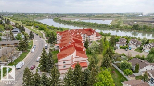 Multi-story residential building featuring a distinctive orange tile roof and light-toned exterior with multiple balconies - 316 2011 137 Avenue, Edmonton, AB - Outdoor With Body Of Water With View