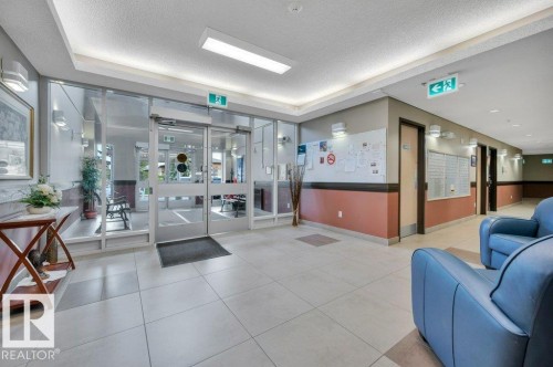 Brightly lit common area featuring large format tile flooring and a glass entry with automatic doors - 316 2011 137 Avenue, Edmonton, AB - Indoor Photo Showing Other Room