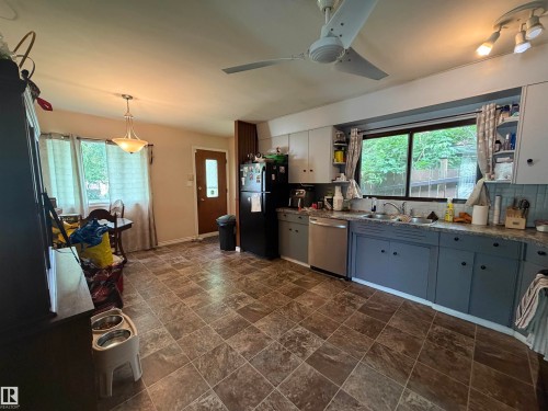 Kitchen area featuring tile flooring, a dual-basin sink, and a large window - 5303 119 Avenue, Edmonton, AB 