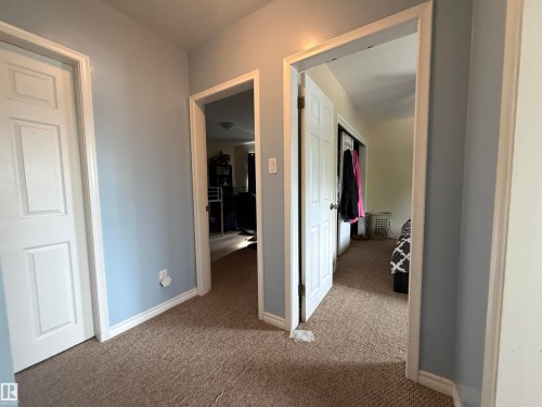 Carpeted hallway with three paneled doors and light blue wall finish - 5303 119 Avenue, Edmonton, AB 
