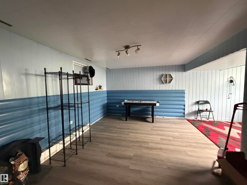 Finished lower level featuring wood-finish flooring, two-tone vertical paneling, and track lighting - 5303 119 Avenue, Edmonton, AB 