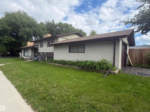 Two-story residence featuring light-toned stucco siding and a prominent attached garage with a brown door - 5303 119 Avenue, Edmonton, AB 