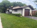 Stucco exterior featuring an attached single-car garage with a brown panel door, an asphalt driveway, and a partially fenced yard - 5303 119 Avenue, Edmonton, AB 