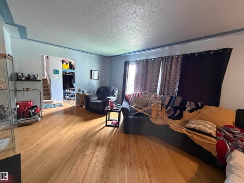 Spacious living area featuring wood-finish flooring, light blue wall paint, and a textured ceiling - 5303 119 Avenue, Edmonton, AB 