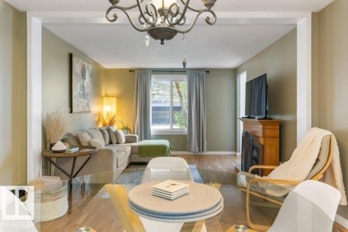 Open-concept living area with wood-finish flooring, a built-in fireplace with a wooden mantel, and a window with natural light - 171 Ridgewood, St. Albert, AB 