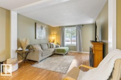 Living area featuring wood-finish flooring, a large window with natural light, and a fireplace with a wood mantle - 