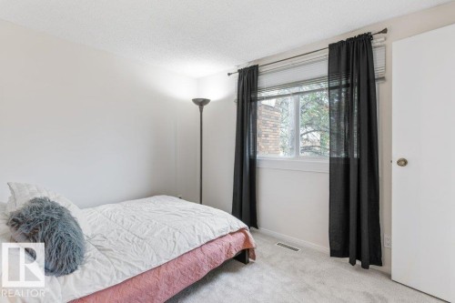 Carpeted room featuring a window with blinds and sheer black curtains, light-colored walls, a ceiling light fixture, and a white door with a brass-toned knob - 171 Ridgewood, St. Albert, AB 