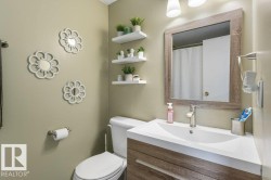Bathroom featuring a wood-finish vanity with an integrated white sink, brushed nickel faucet, framed mirror, and floating wall shelves - 