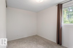 Neutral wall finishes with a single window, overhead lighting, and carpeted flooring - 