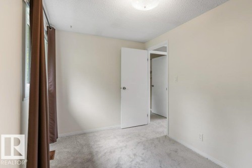 Neutral-toned interior featuring light gray carpeting, white trim, and a window with brown curtains - 171 Ridgewood, St. Albert, AB 
