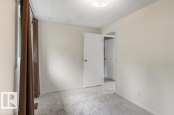 Neutral-toned interior featuring light gray carpeting, white trim, and a window with brown curtains - 