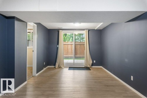 Spacious room with wood-finish flooring and dark blue walls - 171 Ridgewood, St. Albert, AB 