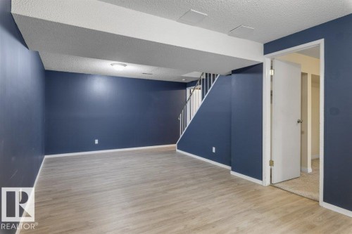 Spacious room with wood-finish flooring, dark blue walls, and white trim - 171 Ridgewood, St. Albert, AB 
