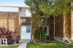 Brick-clad two-story exterior featuring a white entry door and a concrete pathway - 