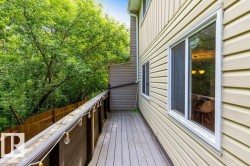 Expansive outdoor deck with composite decking, surrounded by mature trees and a wood privacy fence - 