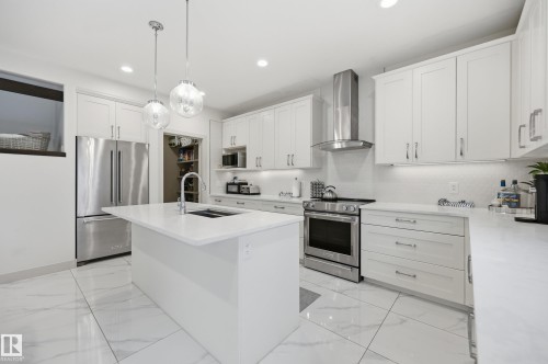 Kitchen featuring a central island, white shaker-style cabinetry, and stainless steel appliances - 76 Jacobs Close, St. Albert, AB 