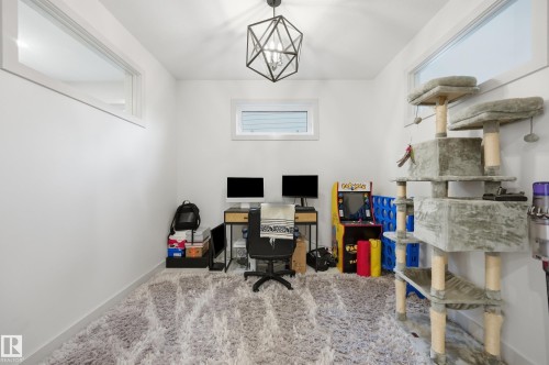 Bright interior room featuring a geometric pendant light fixture, high windows, and plush carpeting - 76 Jacobs Close, St. Albert, AB 