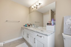 Bathroom vanity featuring a light-toned countertop, white cabinetry with silver-toned hardware, and an integrated sink with a chrome faucet - 