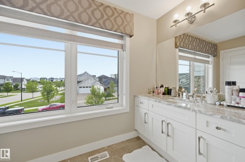 Double vanity with a stone countertop, dual sinks, and white shaker-style cabinetry - 76 Jacobs Close, St. Albert, AB 