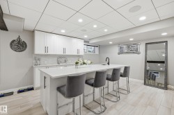 Kitchenette with white shaker cabinetry, quartz countertops, subway tile backsplash, and a breakfast bar - 
