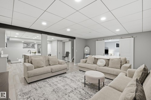Spacious lower-level living area featuring light wood-finish flooring, recessed lighting, and a drop ceiling - 76 Jacobs Close, St. Albert, AB 