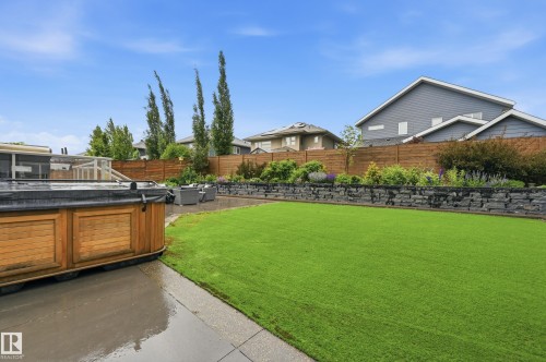 Expansive green lawn framed by a stone retaining wall and mature landscaping - 76 Jacobs Close, St. Albert, AB 
