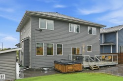 Rear exterior featuring gray siding, a composite deck with glass railings, and a detached shed - 