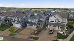 Street view of a residential neighborhood featuring multiple two-story homes with attached garages, manicured lawns, and paved driveways - 