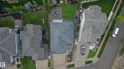 Aerial perspective showcasing a property with a multi-gabled roofline, a paved driveway, and a landscaped front yard - 