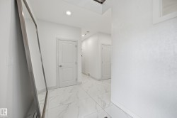 Hallway with large format tile flooring, recessed lighting, and white paneled doors - 