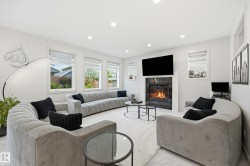 Living area featuring a modern fireplace with a dark surround, white mantel, and mounted television - 