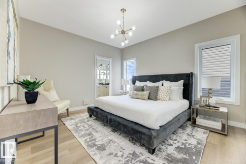 Bedroom featuring a vaulted ceiling with a sputnik chandelier, light wood-finish flooring, and a framed doorway providing a glimpse of an adjacent bath - 519 Ashgrove Circle, Leduc, AB 