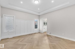 Herringbone wood-finish flooring with a tray ceiling and recessed lighting - 