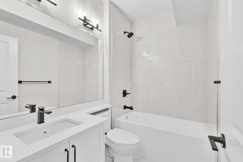 Bathroom featuring a white vanity with an integrated rectangular sink, matte black faucet, and a large mirror - 519 Ashgrove Circle, Leduc, AB 