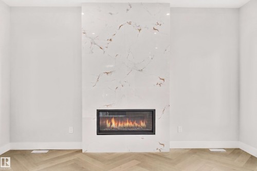 Contemporary fireplace featuring a white and gold veined surround - 519 Ashgrove Circle, Leduc, AB 
