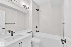 Bathroom featuring a white vanity with an integrated rectangular sink, matte black faucet, and a large mirror - 