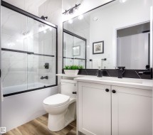 Bathroom with a white vanity featuring shaker-style doors and black hardware - 