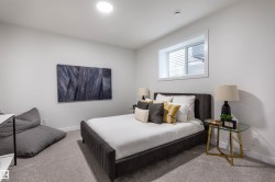 Inviting bedroom featuring plush carpeting, a large window, recessed lighting, and crisp white walls - 