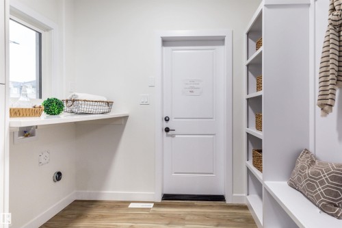 Mudroom featuring built-in shelving, integrated bench seating, and wood-finish flooring - 519 Ashgrove Circle, Leduc, AB 