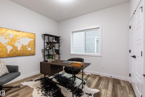 Bright room featuring wood-finish flooring, a white trim window, and a white paneled door with black hardware - 519 Ashgrove Circle, Leduc, AB 
