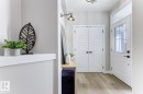 Entryway featuring wood-finish flooring, a white front door with a transom window, and double doors with dark hardware - 519 Ashgrove Circle, Leduc, AB 